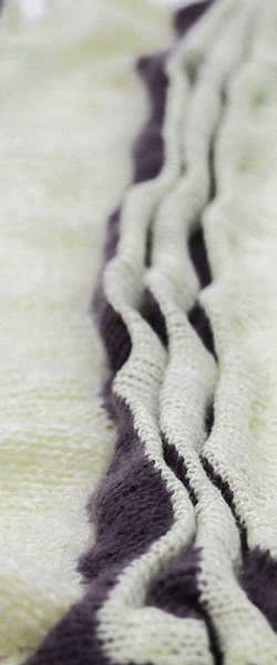 Close-up of a white knit fabric with vertical pleated waves striped in purple and white.